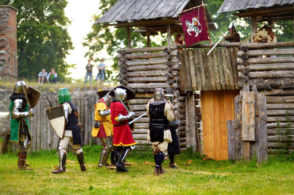 People wearing knight costumes during historical reenactment on annual Medieval Festival, held in Trakai Peninsular Castle. Recreation of medieval town spirit.