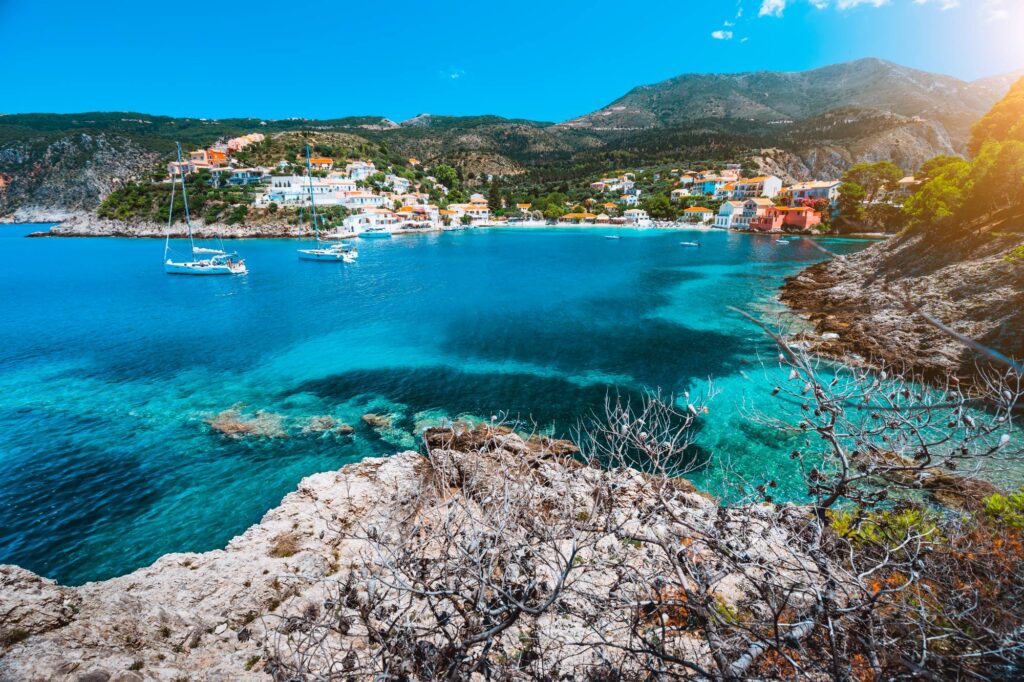 Beautiful Assos village, Kefalonia. Greece. White cruise yachts staying at anchor in beautiful