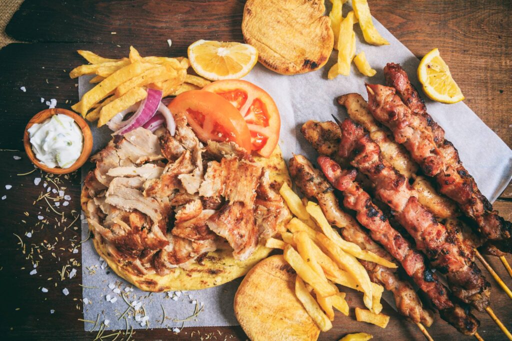 Greek gyros dish and meat skewers on a wooden background