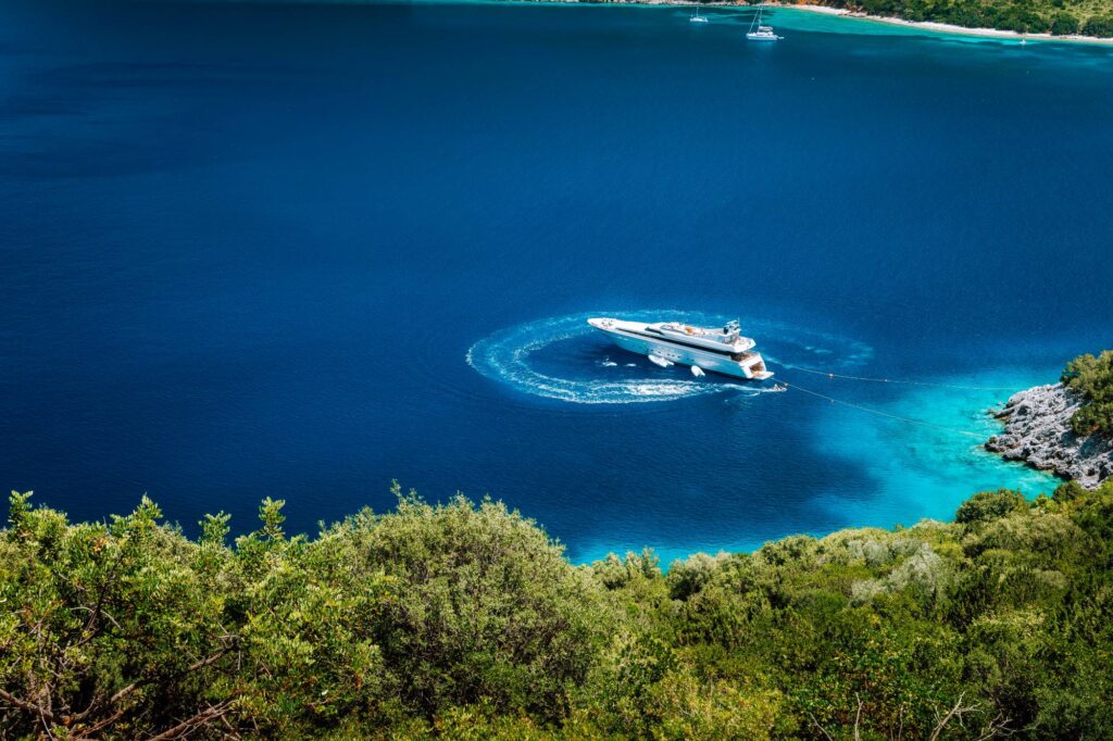 Luxury white yacht sail boat anchoring in a tranquil bay in deep blue water water