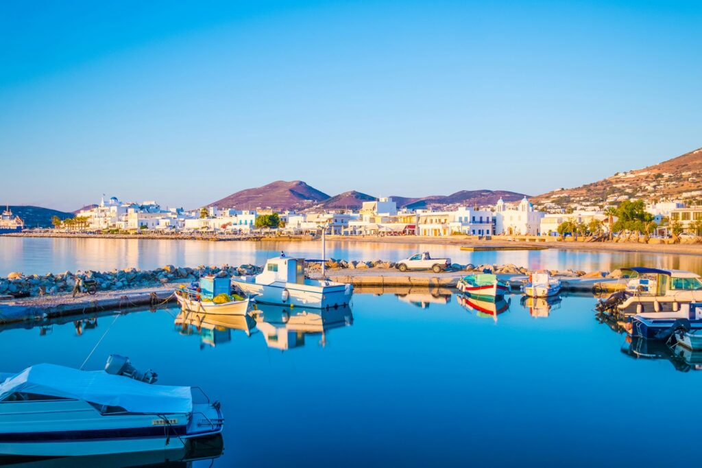 Reflection of an old fishing boat moored at small dock, Paros island, Greece. Beautiful view of fishing boats with reflection on sea surface at sunset