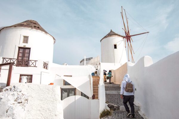 Tourists walking around the streets of oia Greece near a windmill and white buildings